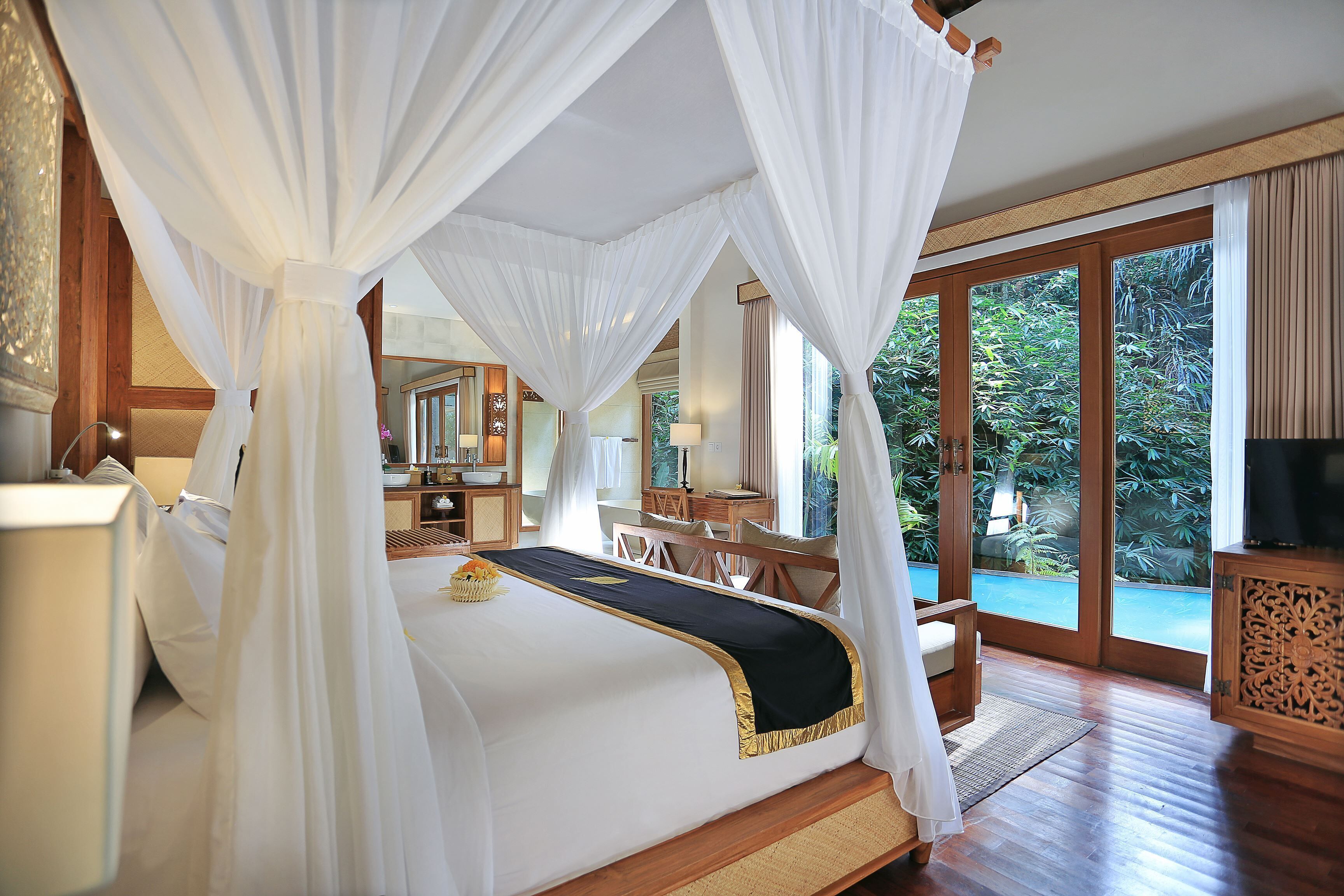 A spacious bedroom with a large bed, a wooden desk, and a television.