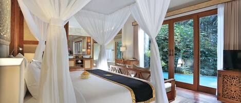 A spacious bedroom with a large bed, a wooden desk, and a television.
