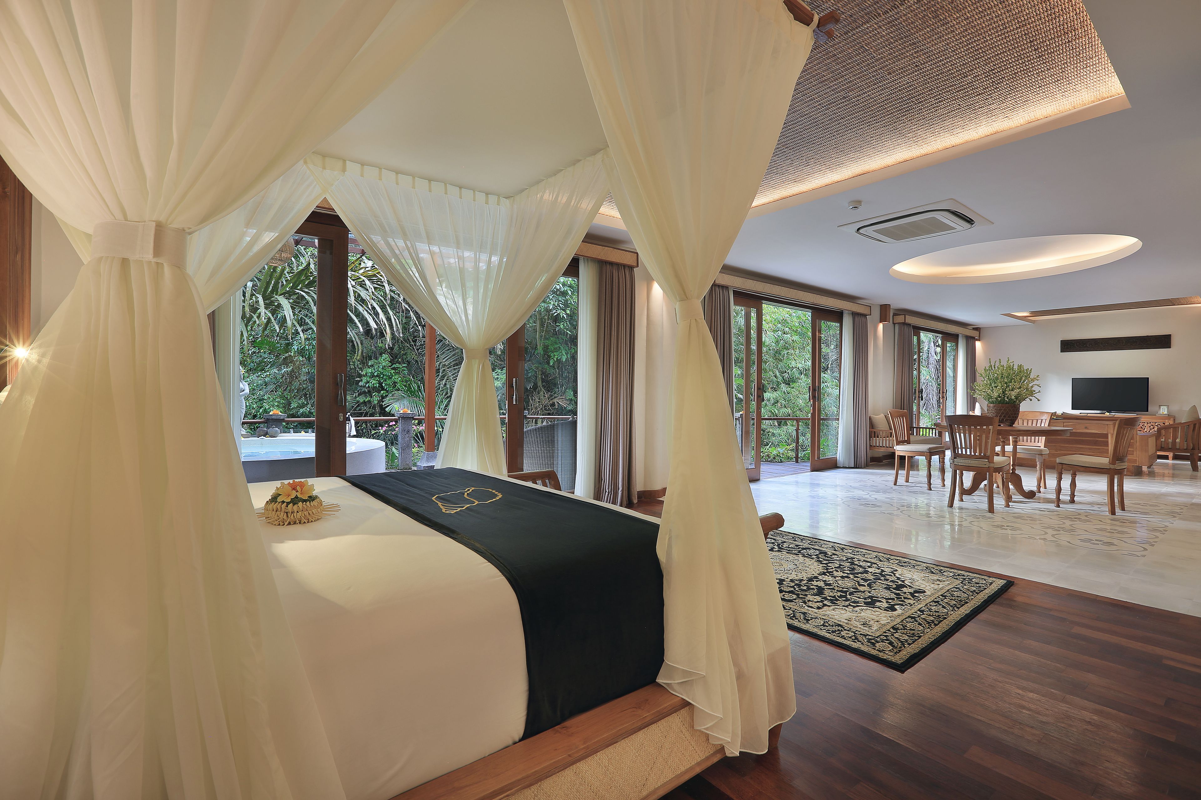 A spacious bedroom with a large bed, a dining area, and a view of greenery.