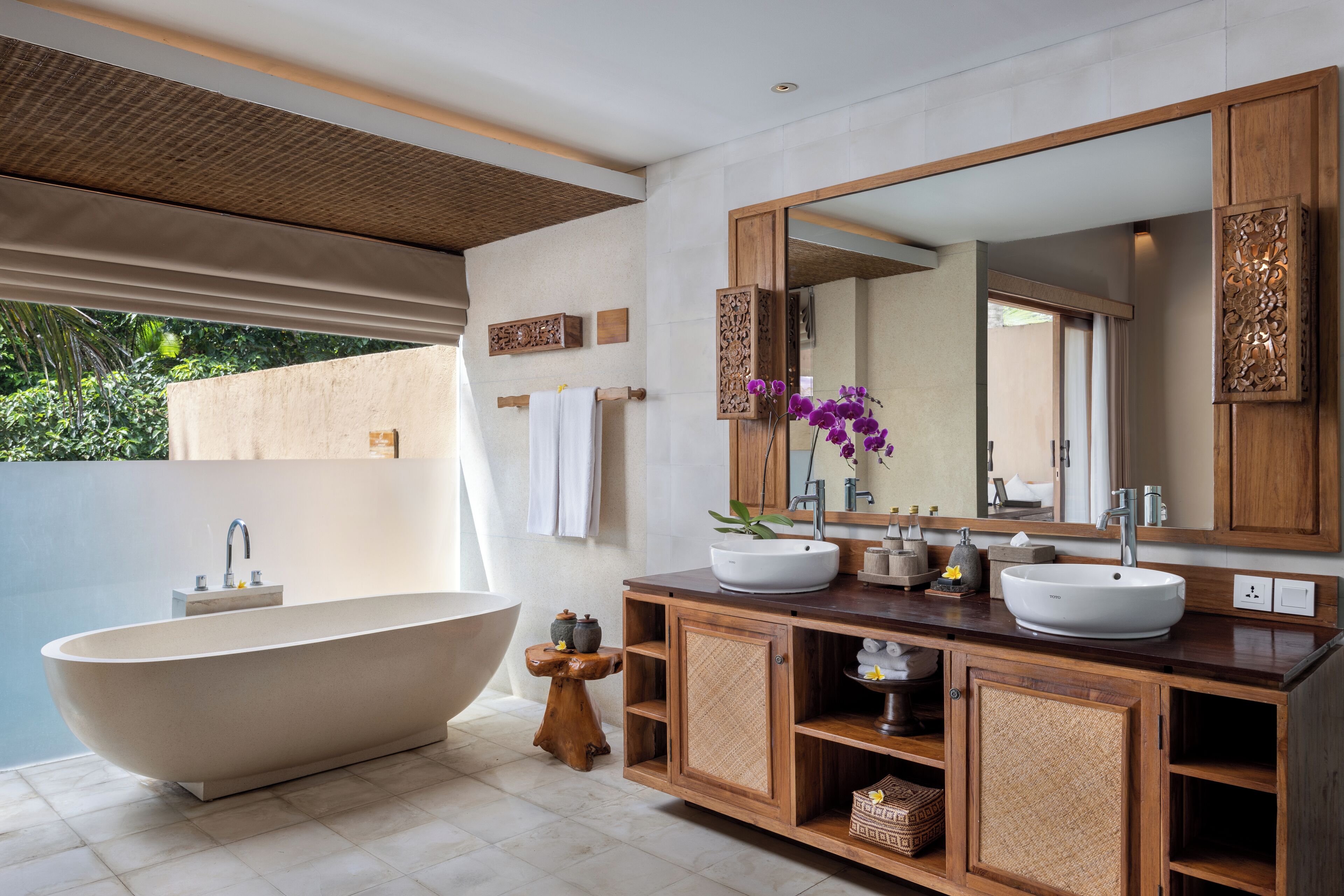 Ein modernes Badezimmer mit freistehender Badewanne, einem geräumigen Waschtisch mit zwei Becken und einem Spiegel darüber.