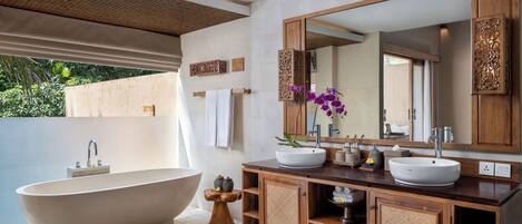 Ein modernes Badezimmer mit freistehender Badewanne, einem geräumigen Waschtisch mit zwei Becken und einem Spiegel darüber.