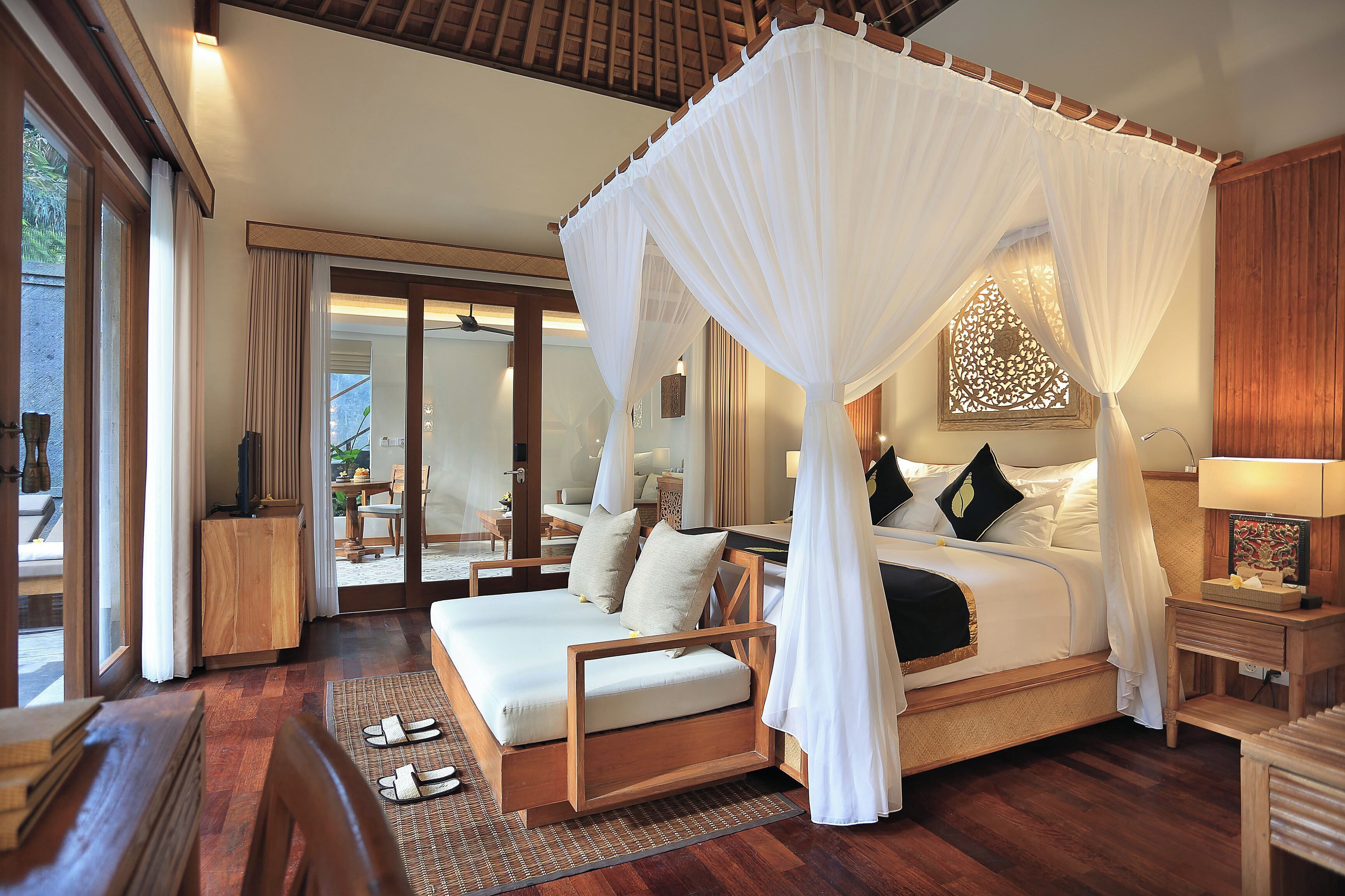 A spacious bedroom with a canopy bed, wooden furniture, and a view of the outdoor area.