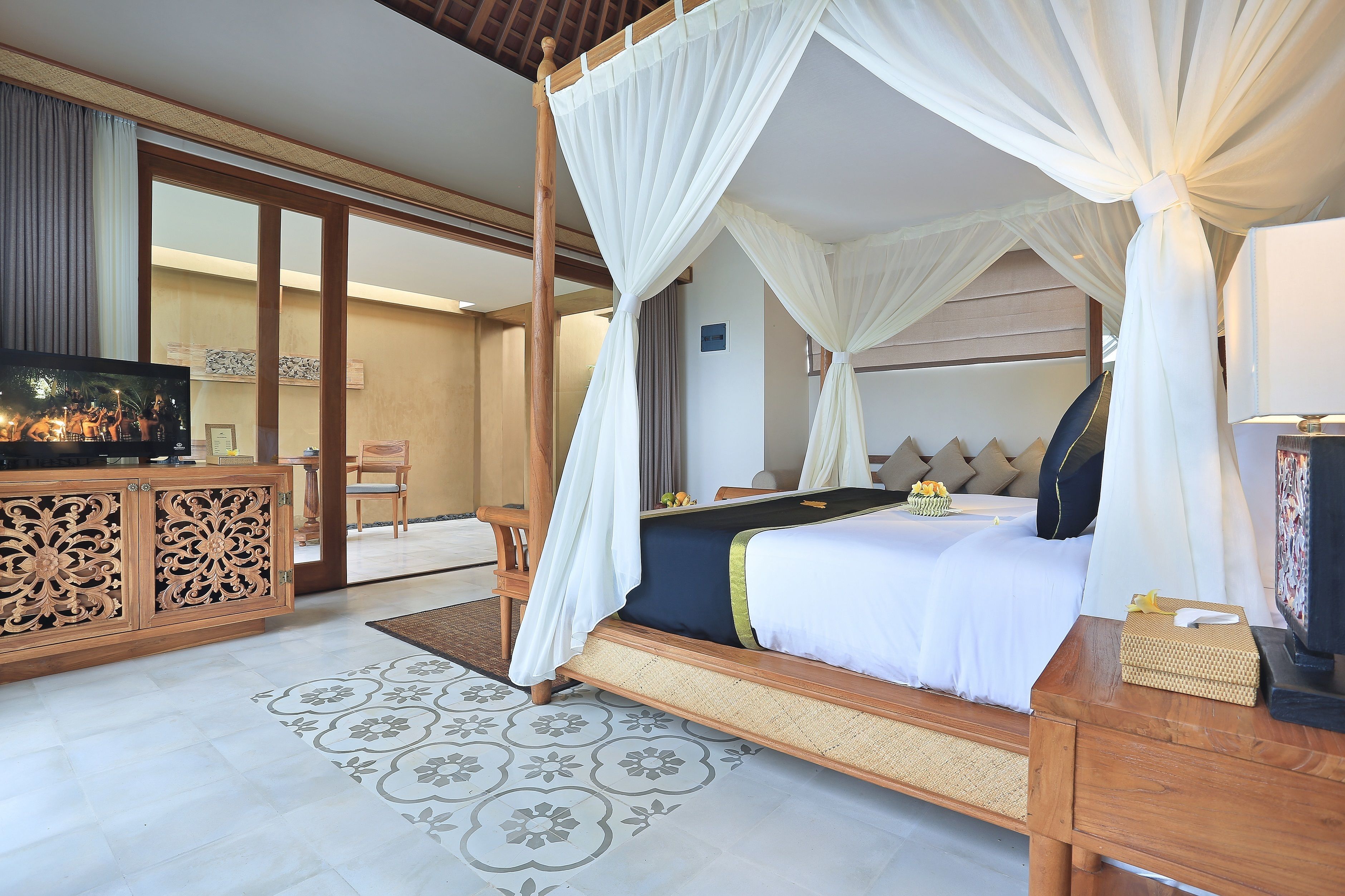 A bedroom with a four-poster bed, a television, and a wooden cabinet.