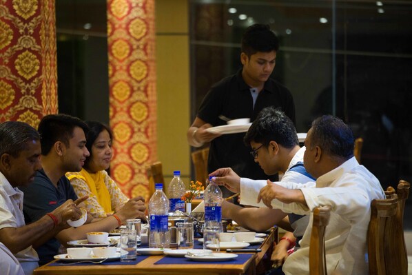 A group of people dining at a table with water bottles, plates, and glasses.