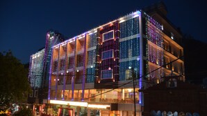 Et hotel med flere etager, moderne facade, store vinduer og en restaurant i stueetagen.