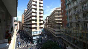 A multi-story building with balconies, a central spiral staircase, and a street below with parked cars and a pedestrian crossing.