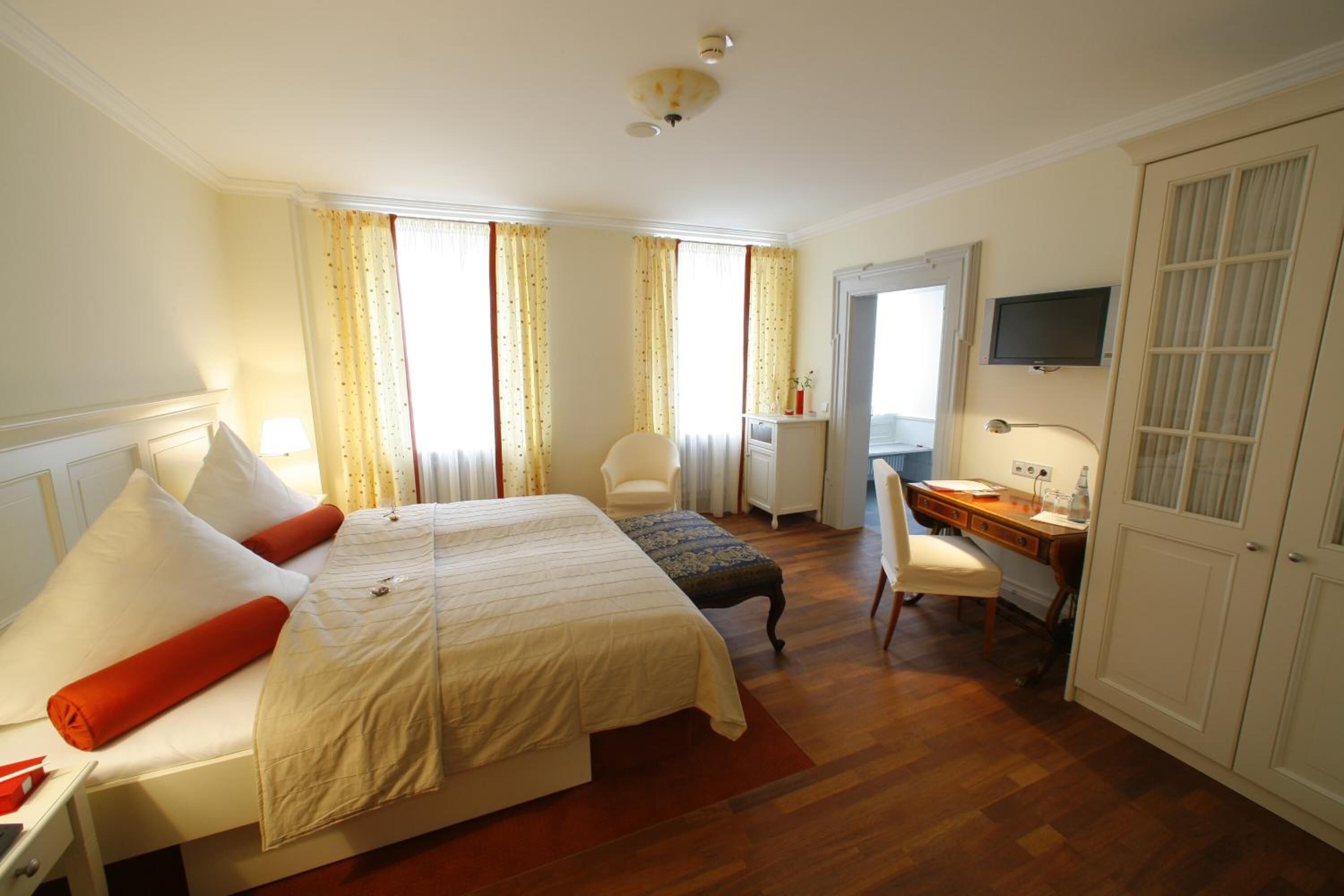 Una camera d'albergo con un letto matrimoniale, una scrivania con sedia, una televisione e un armadio.