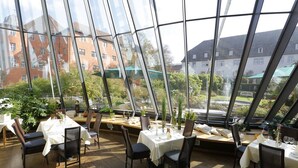 Een restaurant met grote glasramen, houten tafels en stoelen.