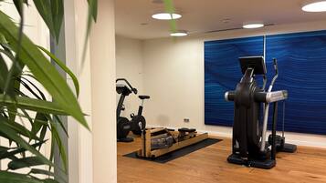 A gym with exercise equipment, a blue wall, and wooden flooring.