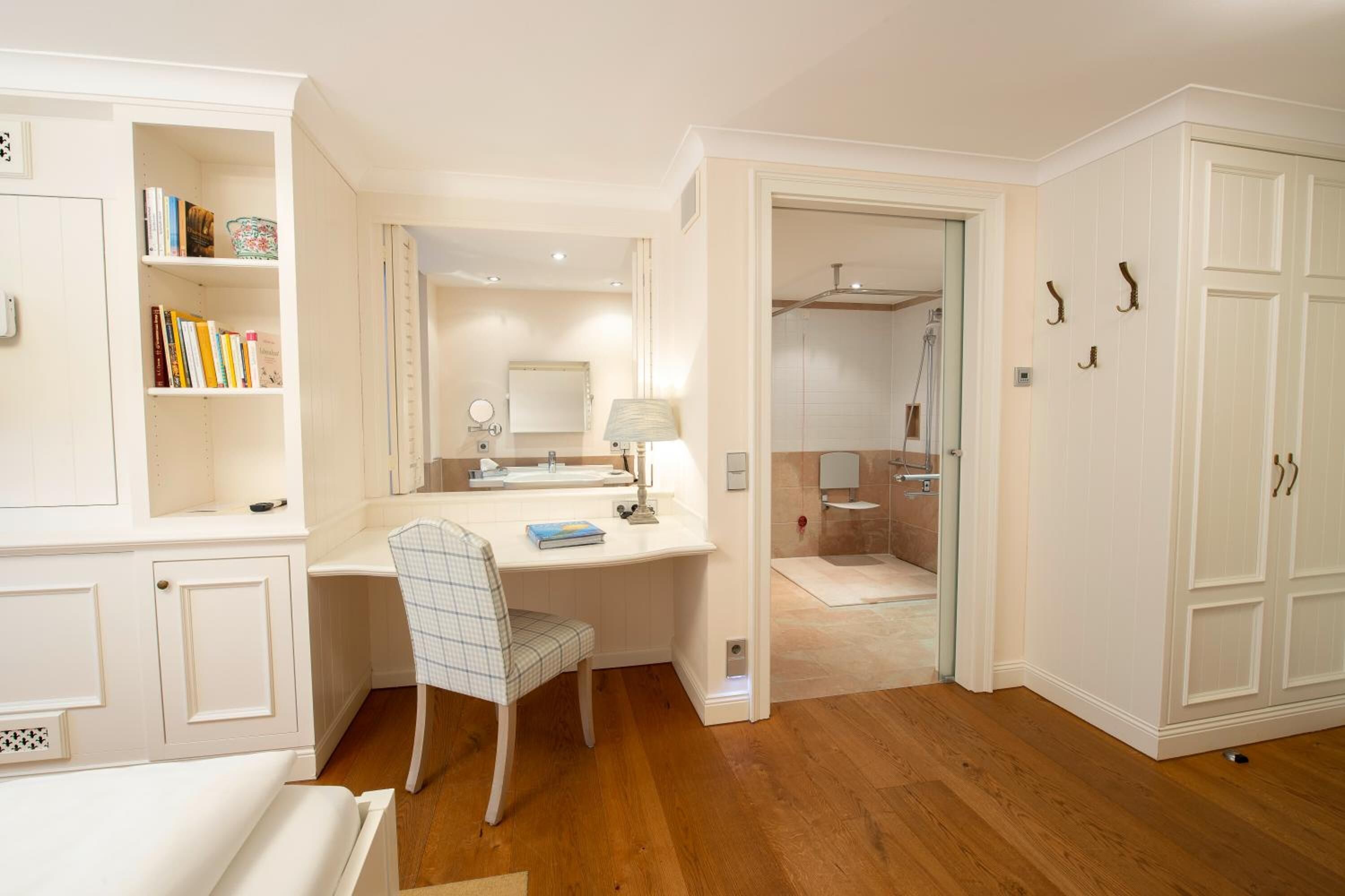 A well-lit room with a desk, chair, and a bookshelf.