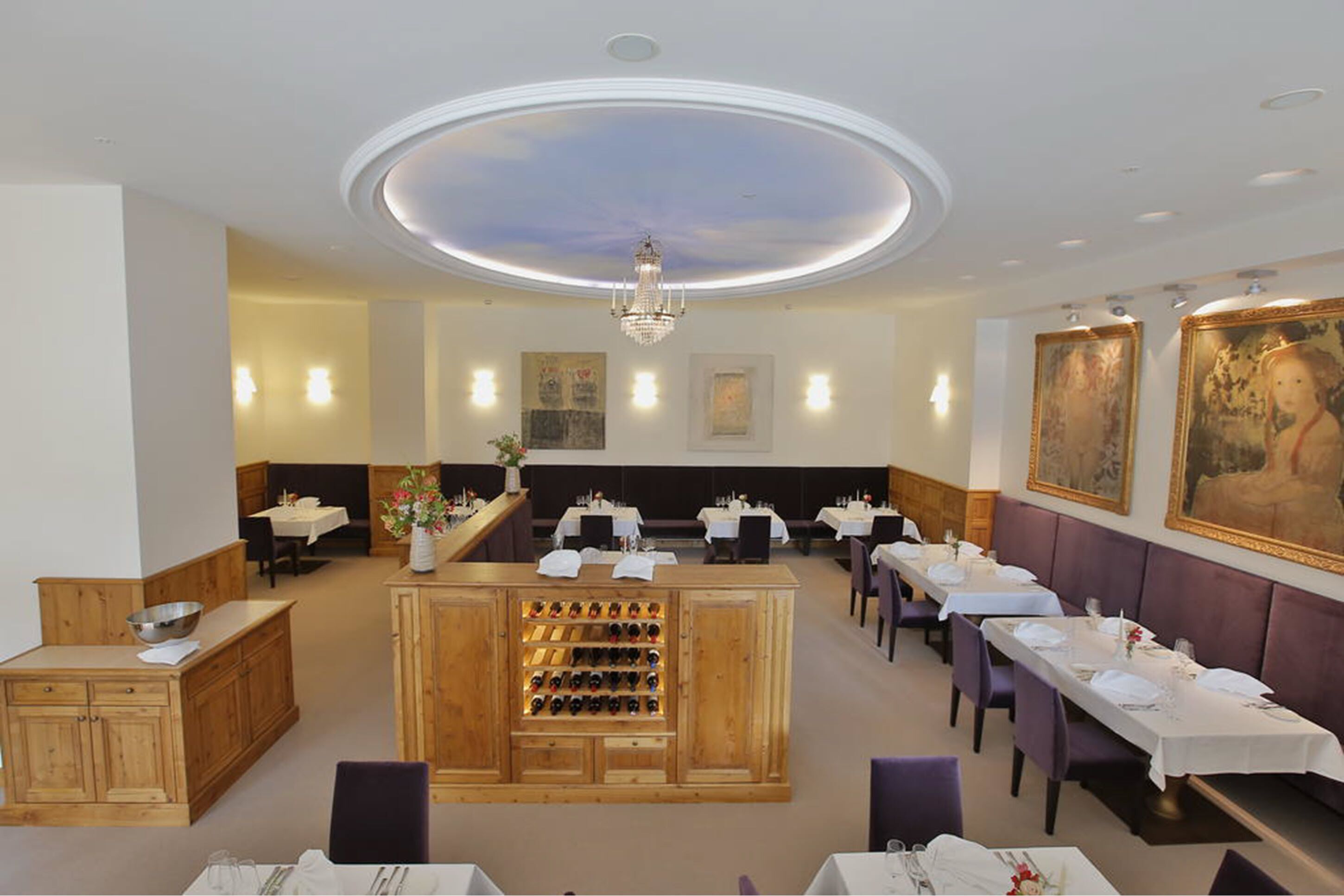 A restaurant with a central bar area, multiple dining tables, and a ceiling with a circular light fixture.