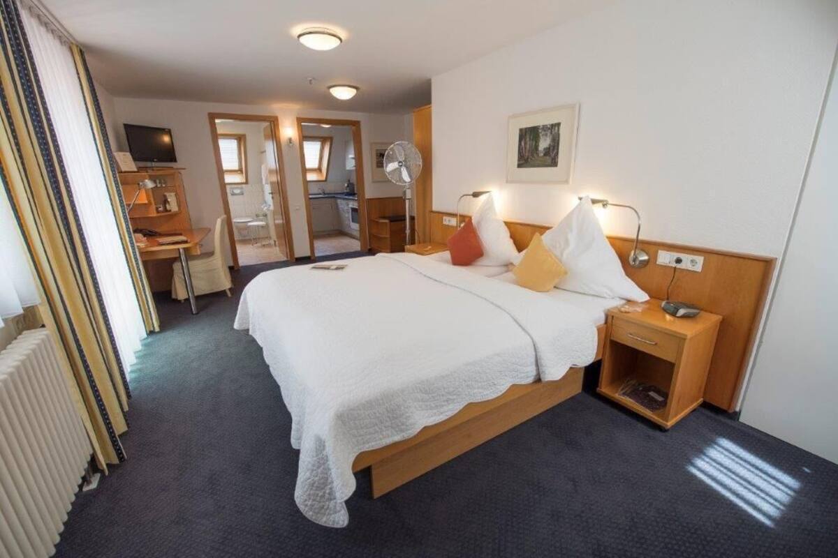 Une chambre d’hôtel avec un grand lit, une table de chevet, une lampe et un petit bureau avec une chaise.
