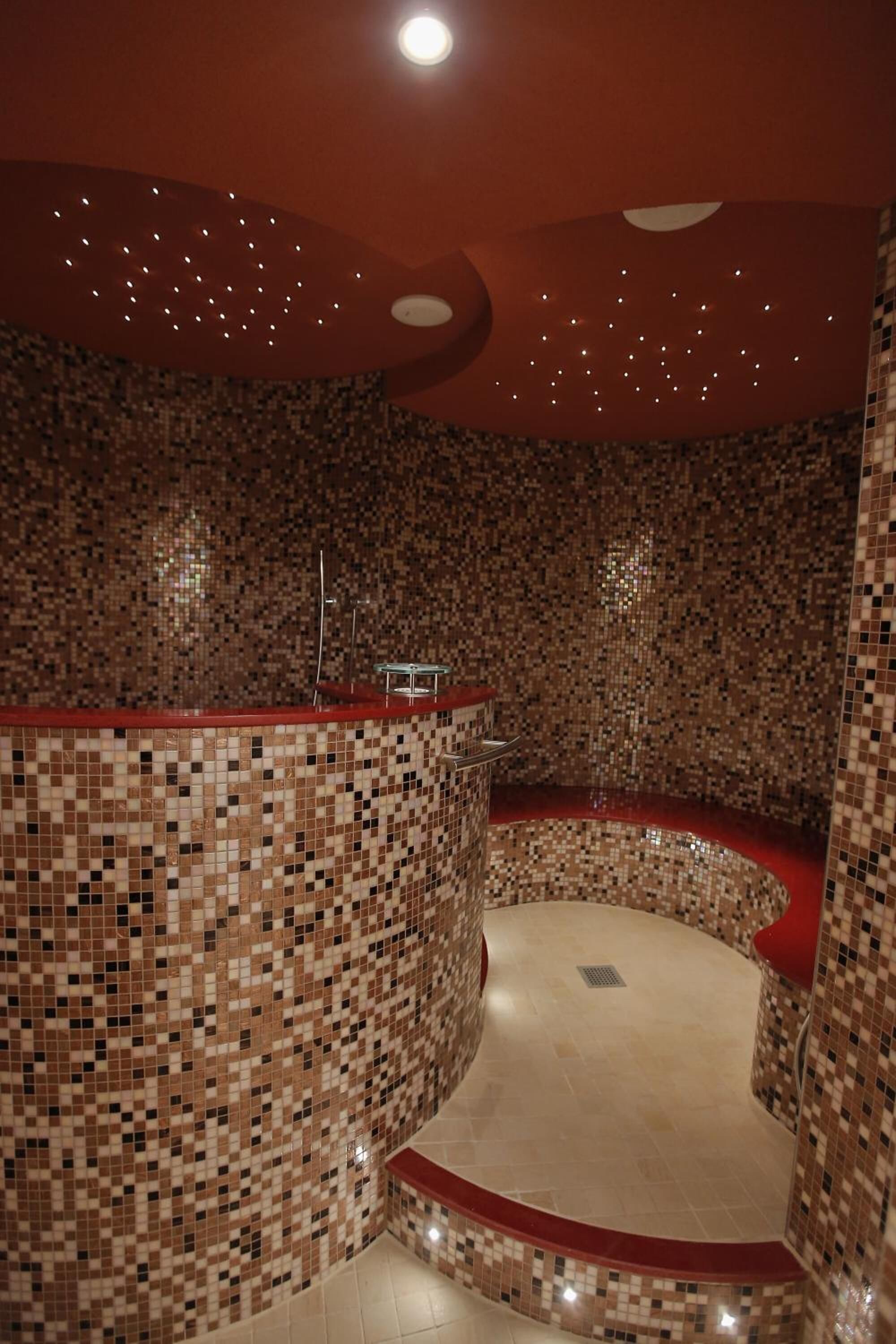 Una habitación circular con paredes de mosaicos y suelo rojo.