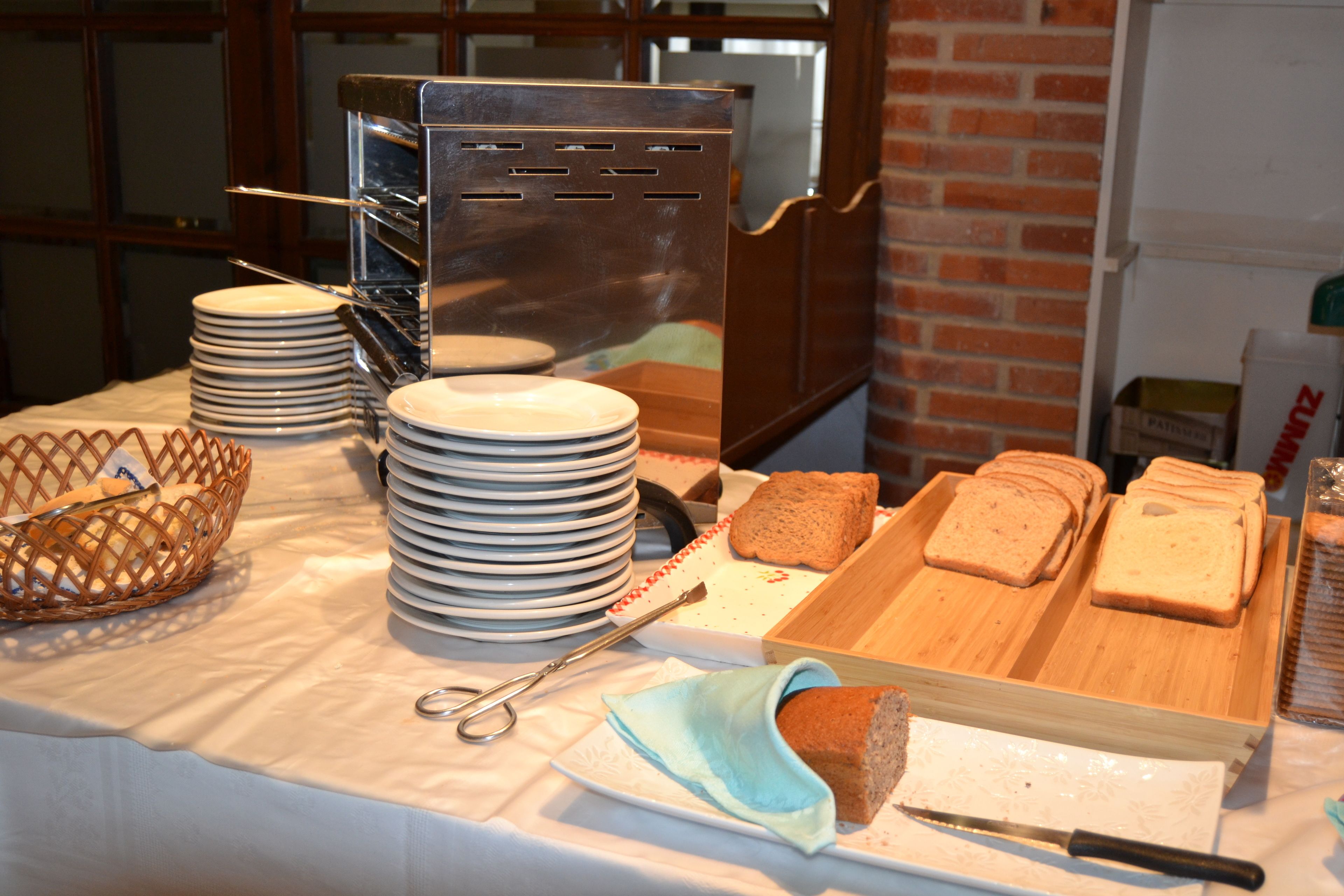 A buffet setup with plates, bread, and a knife on a table.
