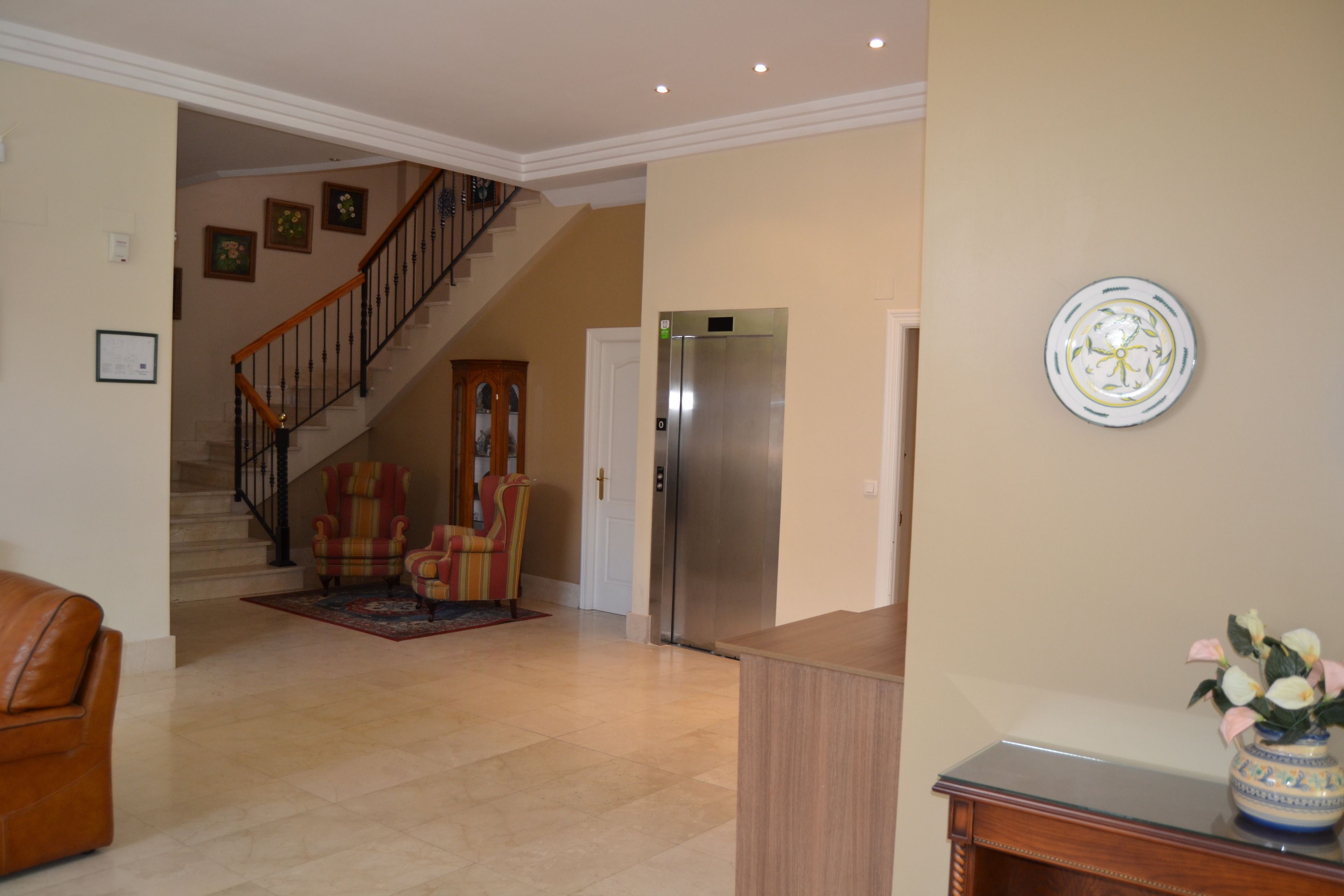 Amplia sala de estar con una escalera, un refrigerador y un plato decorativo en la pared.