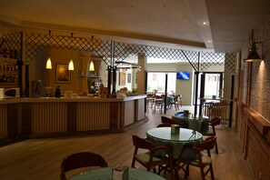 Een restaurant met een bar, meerdere tafels en stoelen.