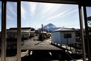 A view of a residential area with traditional houses, a small white building, and a mountain in the background.