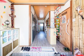 A hallway with wooden floors, a welcome sign, a decorative wooden door, and a wall with various hanging ornaments.
