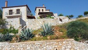A stone building with a balcony and a smaller structure on a hillside. - Rathimata villas (West Mani)