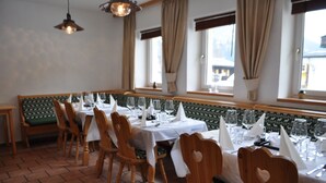 Un restaurante con sillas y mesas de madera dispuestas para comer, amplias ventanas con cortinas y un suelo de baldosas.