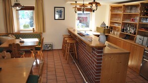 Una cocina con barra, taburetes de madera, una mesa de comedor y suelo de baldosas.