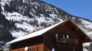 Una cabaña de madera con balcón, rodeada de montañas nevadas.
