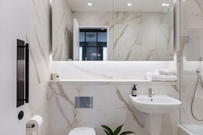 Large Studio Apartment | Badkamer | Een bad/douchecombinatie, designer toiletartikelen, een haardroger