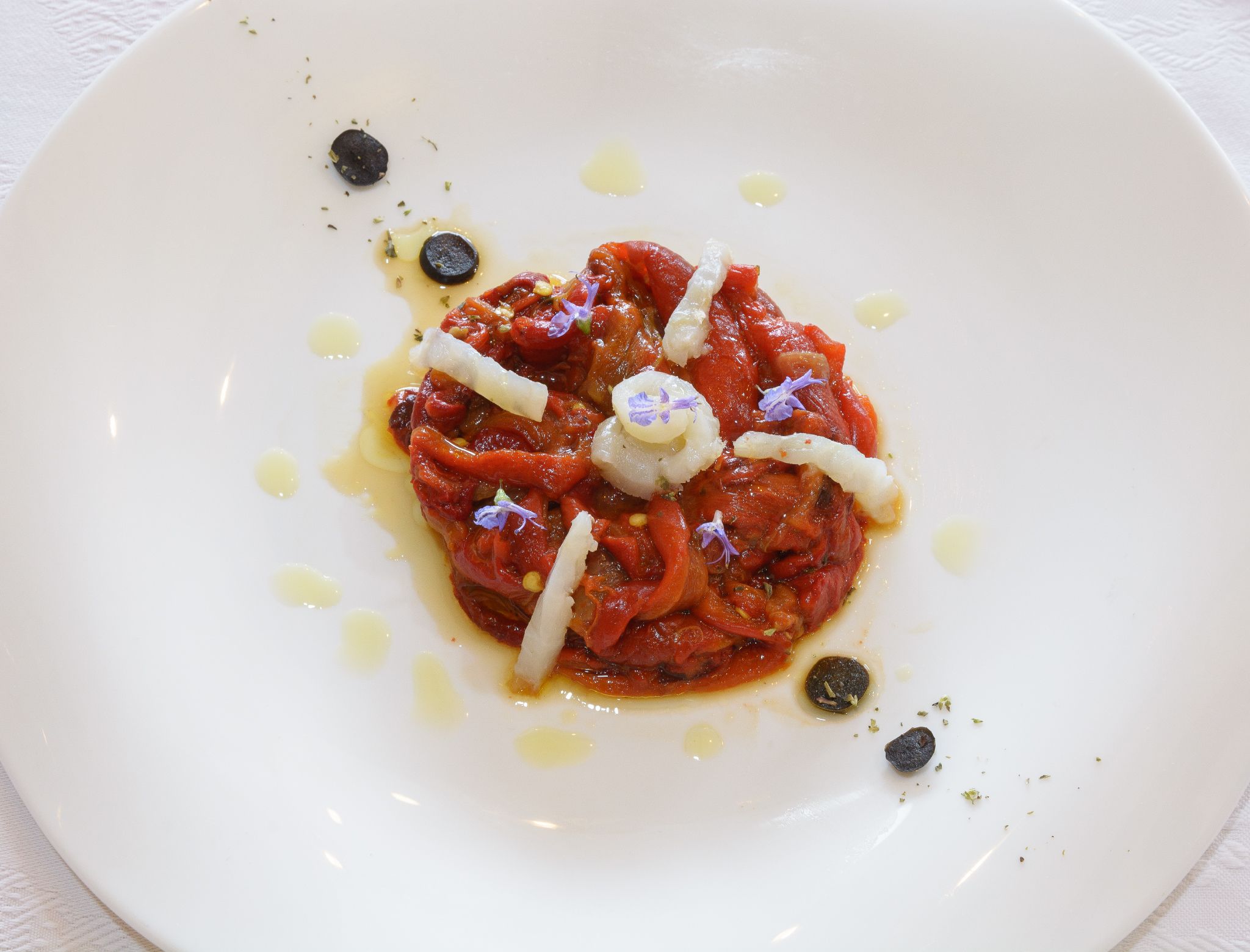 A plate of food with a sauce, garnishes, and olive oil.