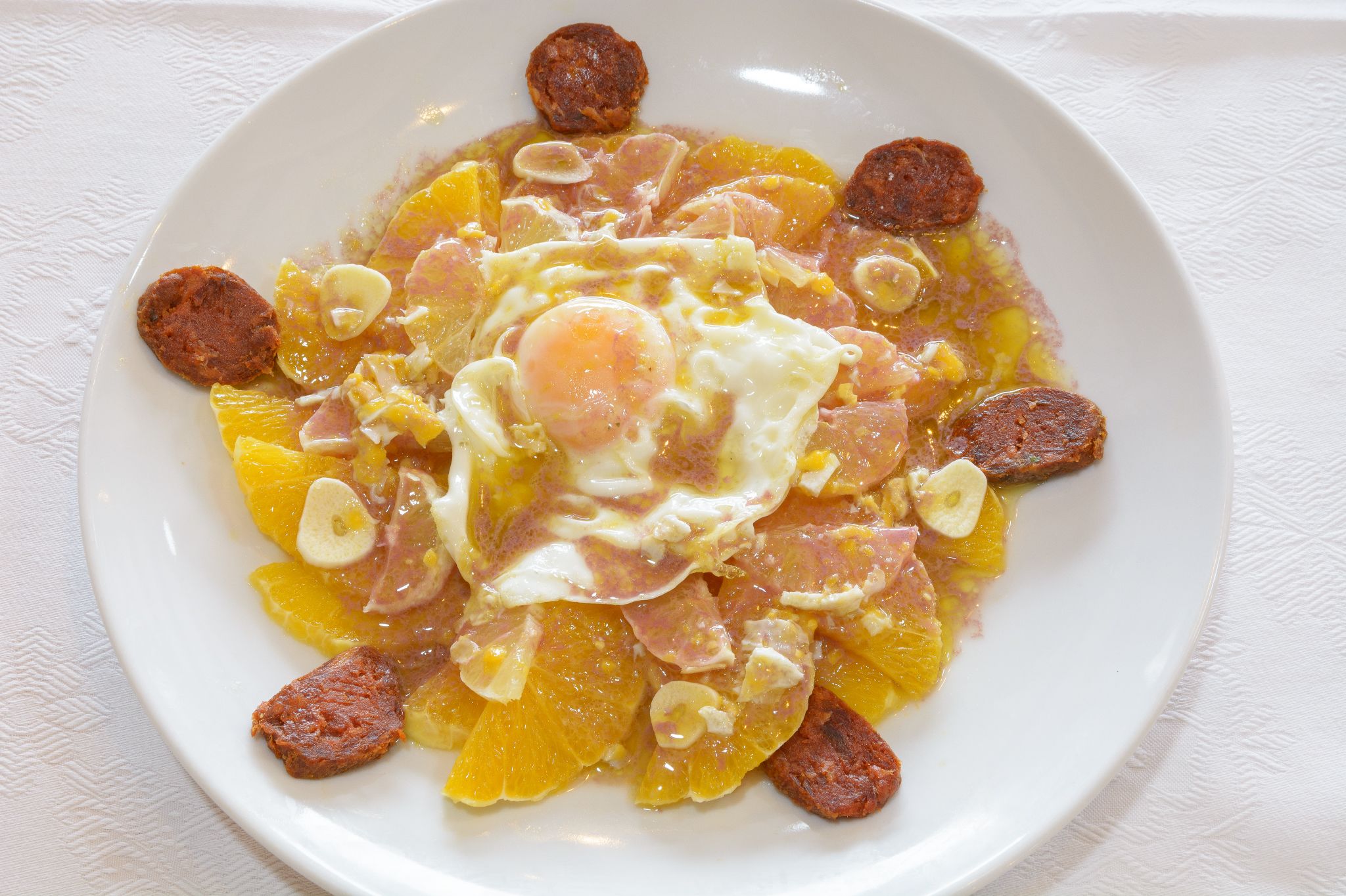 A plate of food with eggs, sausage, and oranges.