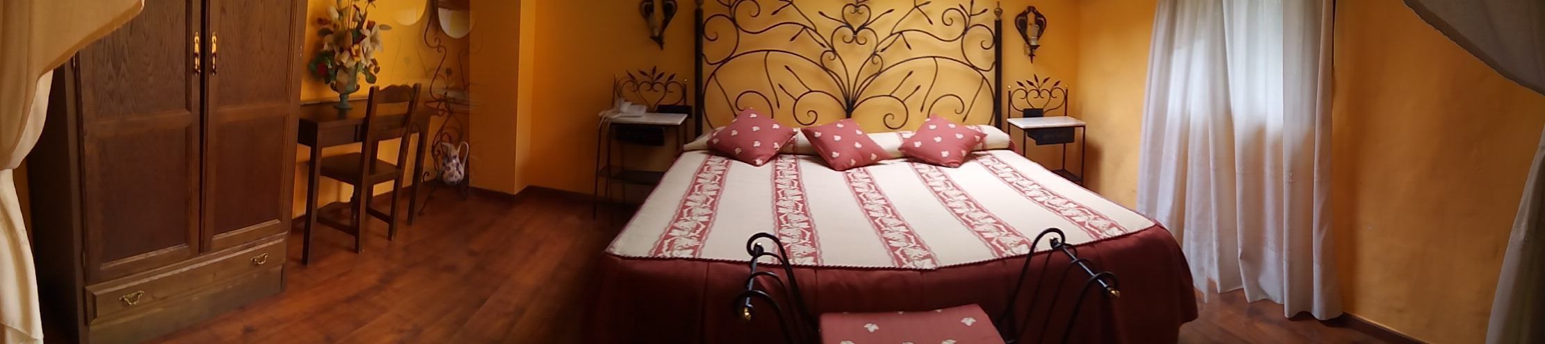 Un dormitorio con piso de madera, una cama con colcha estampada, una mesita de noche, una silla y un armario.