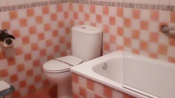 A bathroom with a toilet, a bathtub, and a shelf with towels.