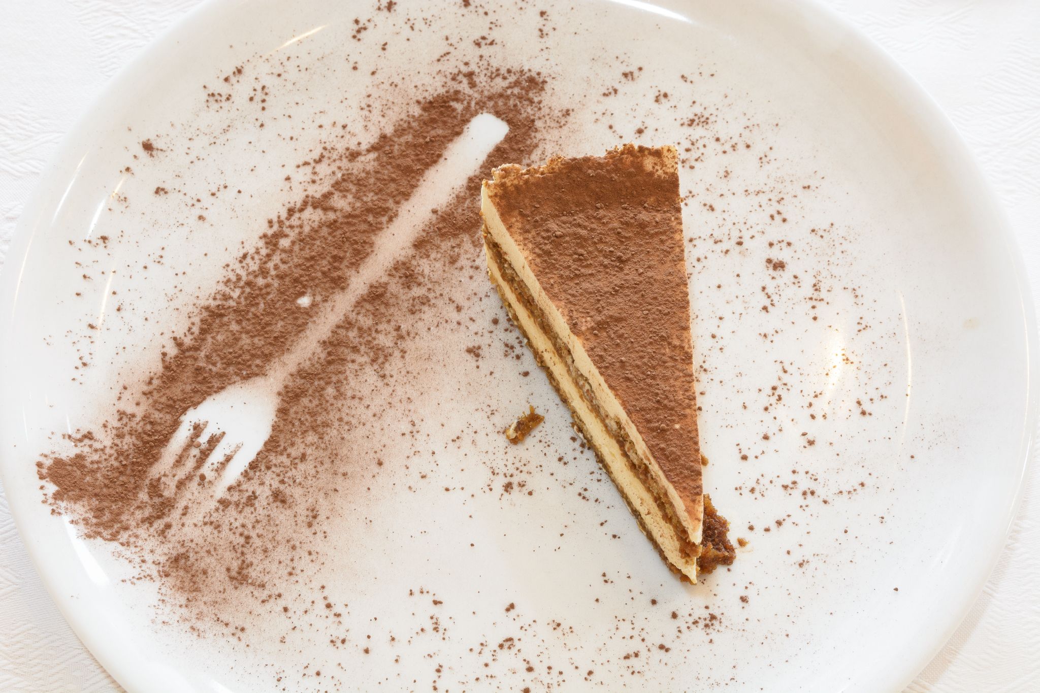 Una porció de tiramissú sobre un plat blanc amb un garrot.