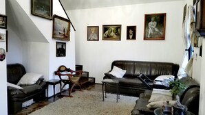A living room with a black leather sofa, a wooden chair, a small table, and a staircase leading to an upper level.