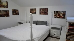 A bedroom with a large bed, white nightstands, and a bookshelf.