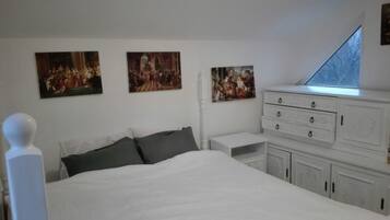 Un dormitorio con una cama grande, un aparador y tres cuadros en la pared.