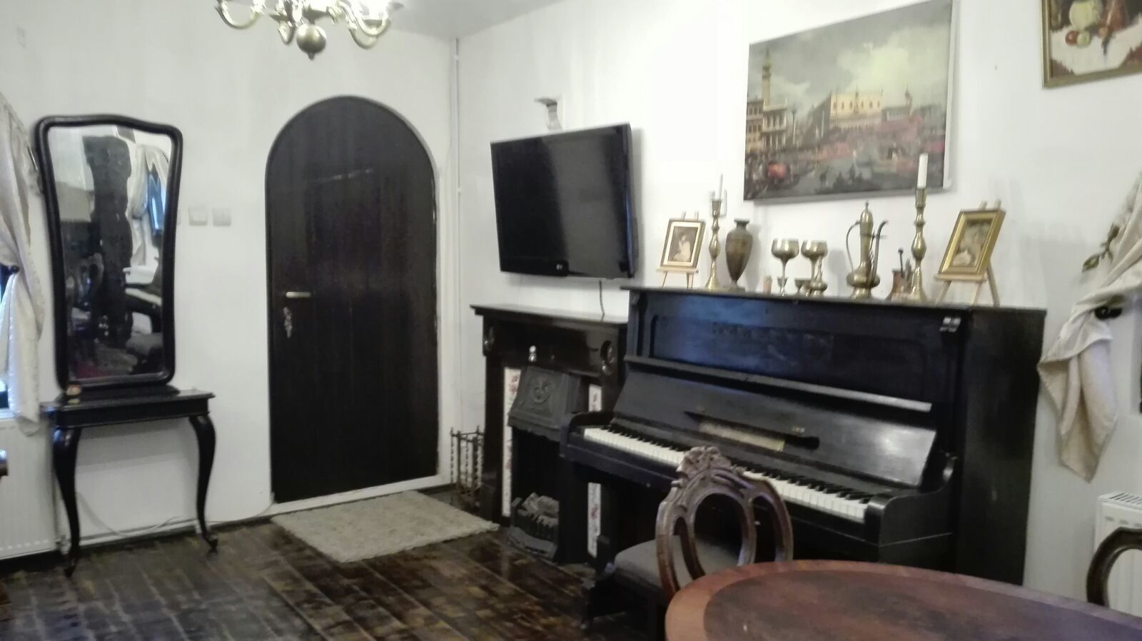 A living room with a piano, a television, and a door.