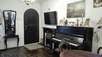 A living room with a piano, a television, and a door.
