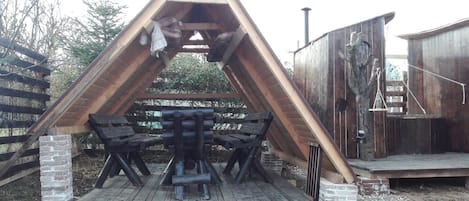 Ein hölzerner Pavillon mit einem dreieckigen Dach und einem Tisch mit Stühlen darunter.
