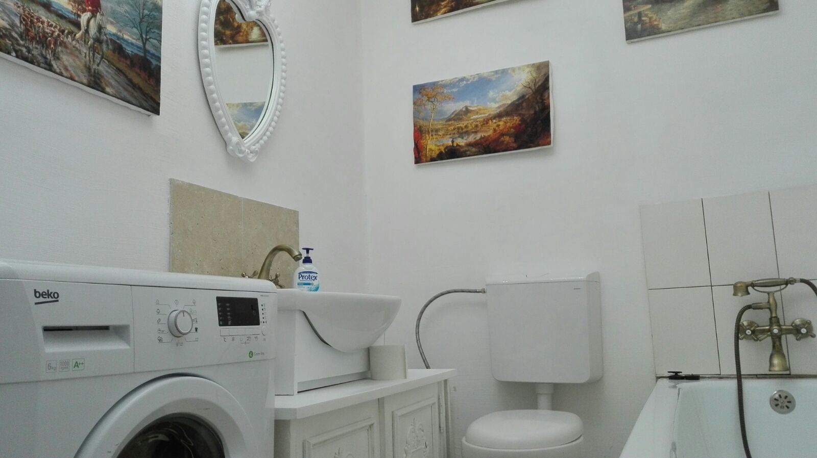A bathroom with a washing machine, a sink, a toilet, and a shower.