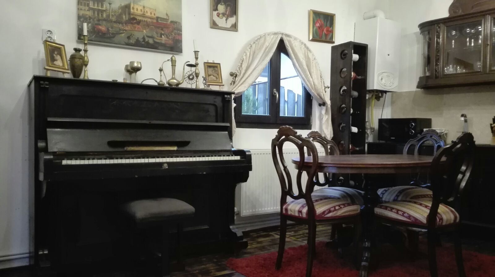 A dining area with a piano, chairs, a table, and a window with curtains.