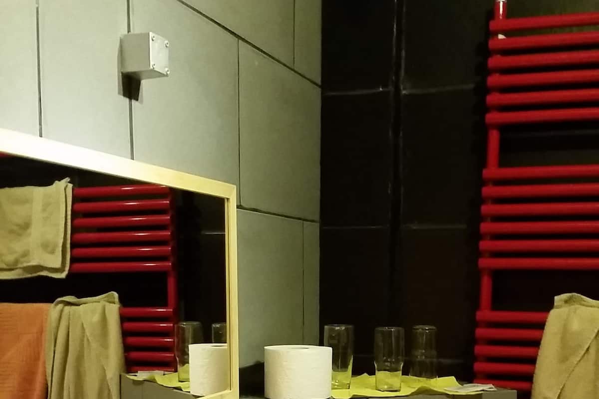 Ein Badezimmer mit Waschbecken, Spiegel, Handtuchhalter und Toilette.