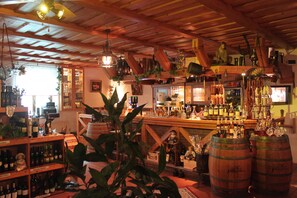 A bar with wooden shelves stocked with bottles and a variety of bar tools. - Hotel und Restaurant die Burg (Ehrenfriedersdorf)