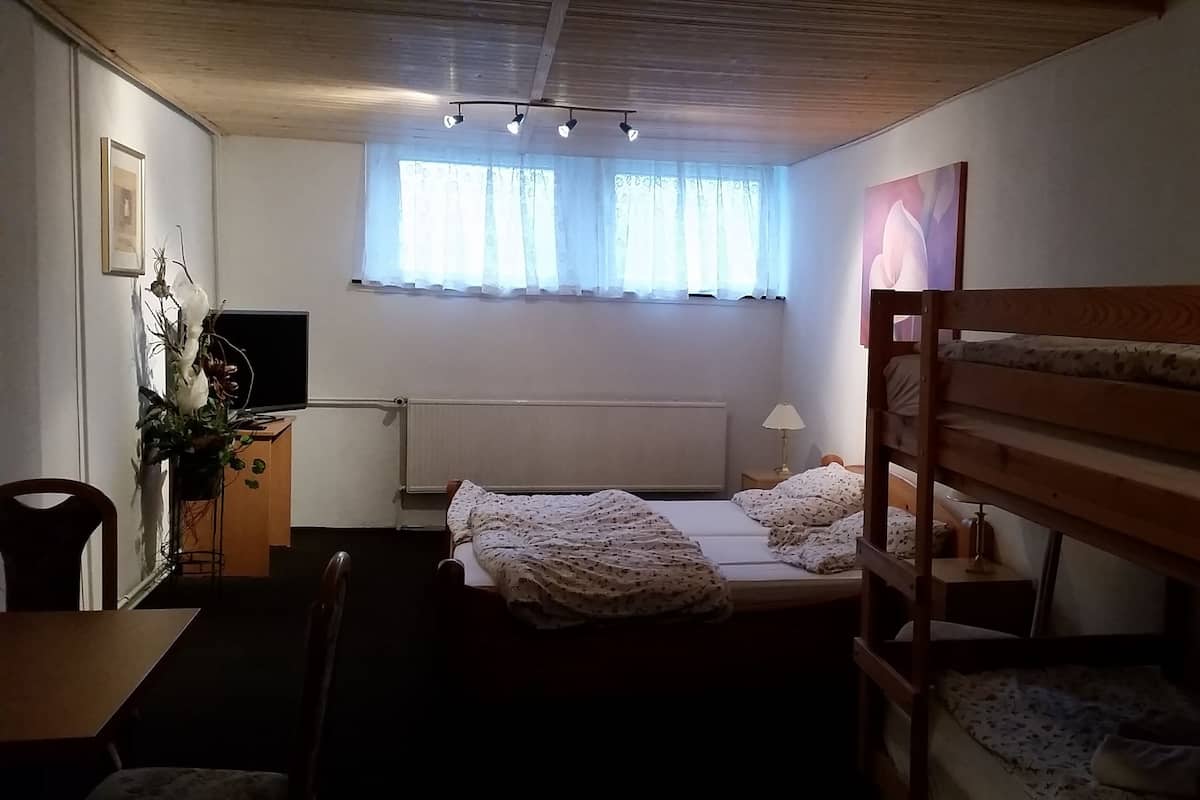 Ein Schlafzimmer mit Etagenbett, Schreibtisch, Stuhl, Heizkörper und einem Fenster mit Vorhängen.
