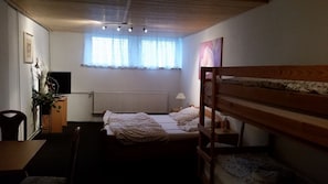 Une chambre avec un lit superposé, un bureau, une chaise, un radiateur et une fenêtre avec des rideaux.
