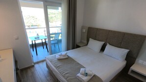 Une chambre d’hôtel avec un lit, une table de chevet, un bureau et une vue sur l’extérieur.