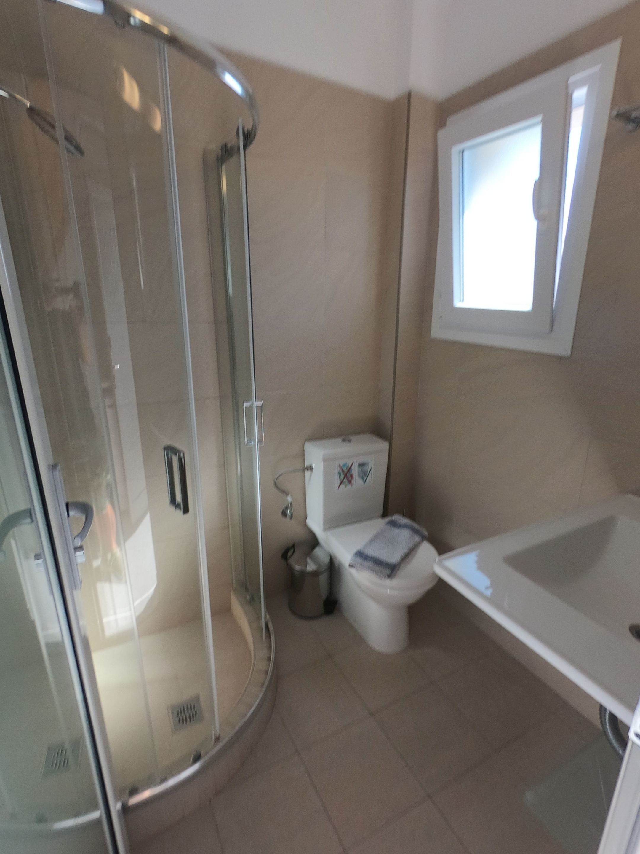 Kylpyhuone, jossa on lasiseinällä varustettu suihku, wc ja kylpyamme.