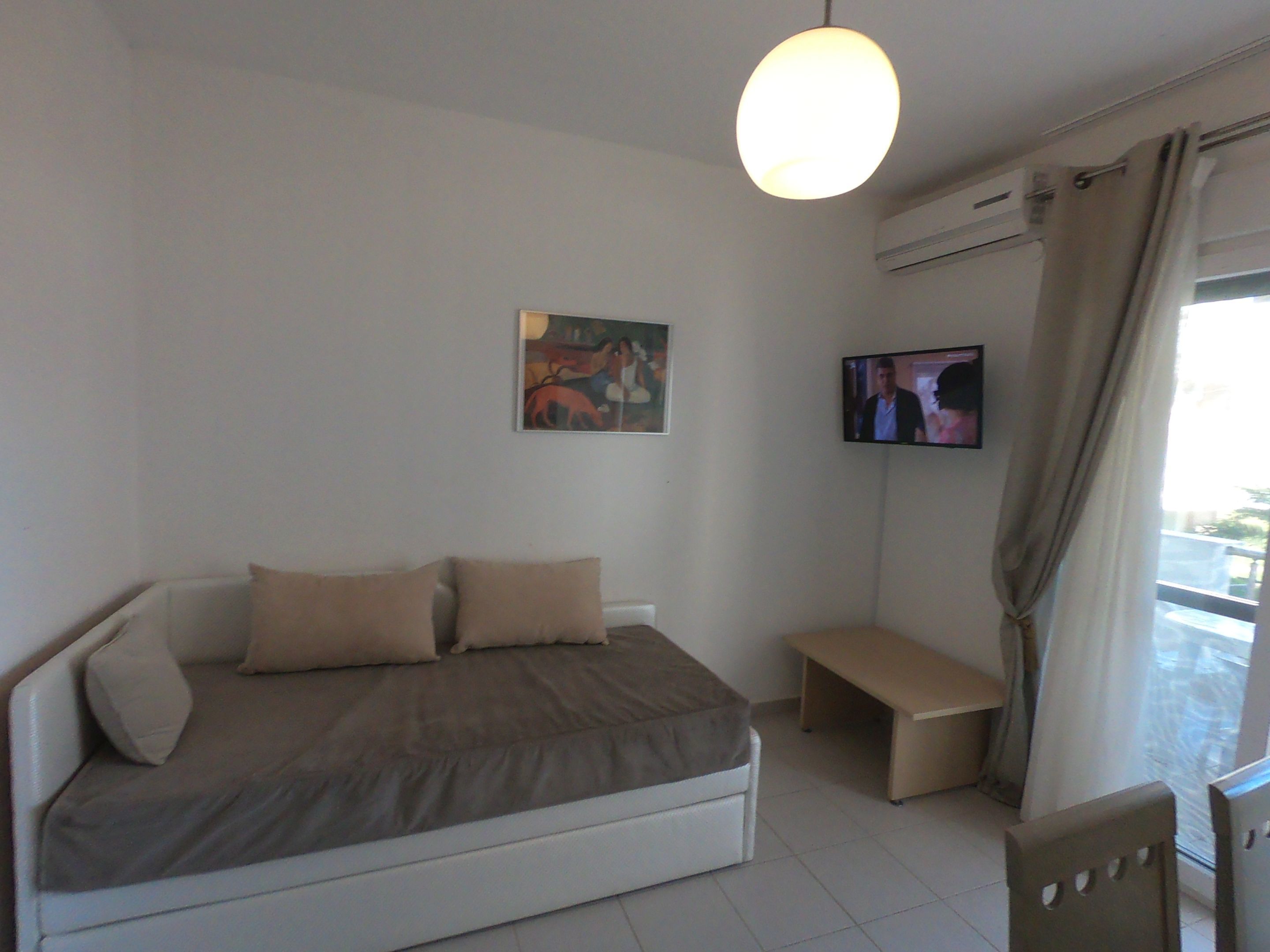 Ein modernes Schlafzimmer mit Bett, Bank, Fernseher und einem Gemälde an der Wand.
