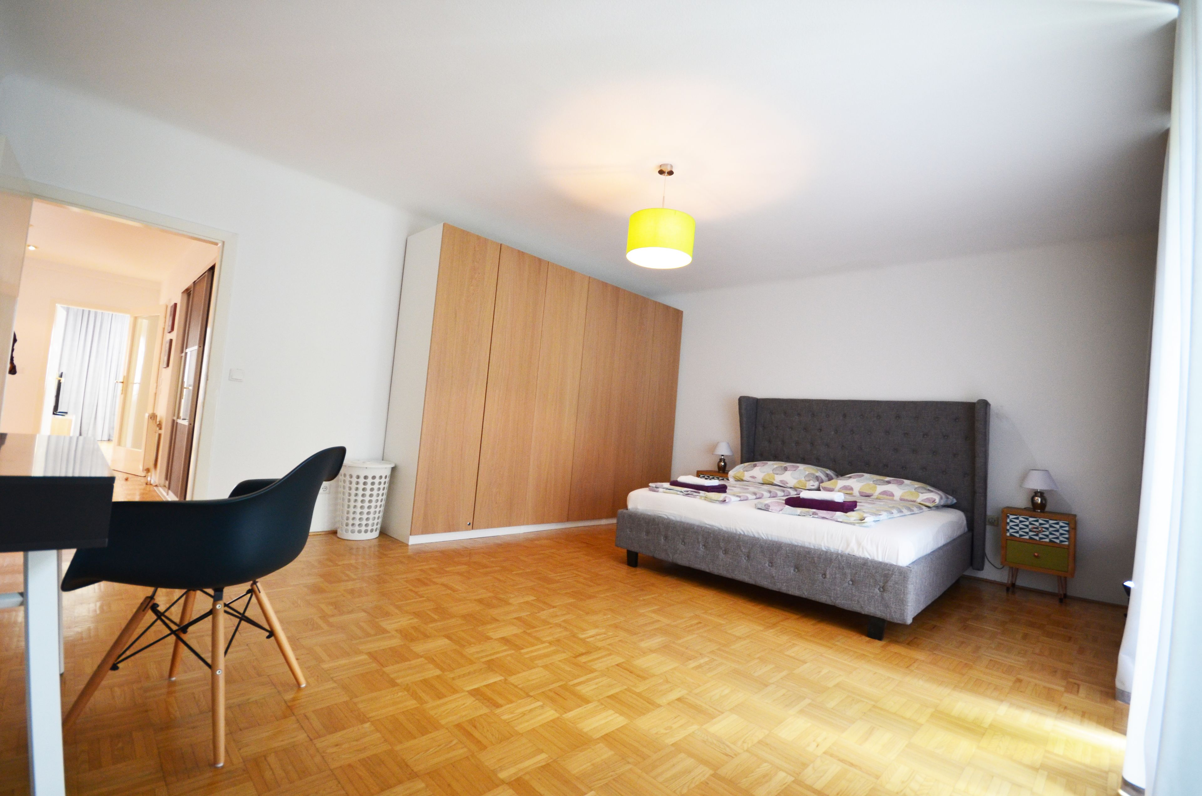 A bedroom with a bed, a desk, and a chair.