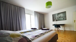 Een slaapkamer met een groot bed, een bureau en een stoel.