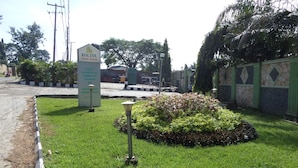 A well-maintained lawn with a sign for KOLTol Guest House, indicating amenities like a conference hall, swimming pool, and restaurant. - Koltol Guest House (Ibadan)